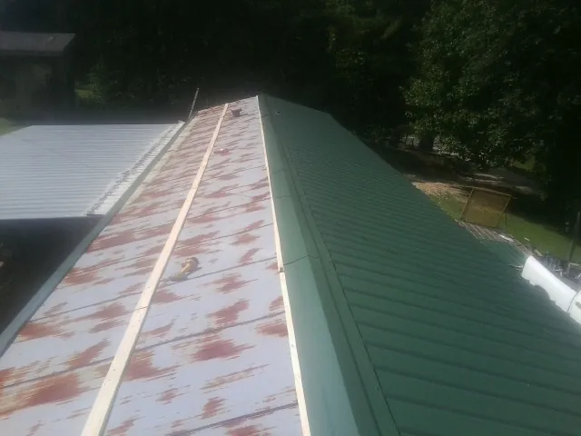 Old rusted panels beside newly installed green metal roofing — Wind Damage Roof Repair by Roofing Brothers in Parker